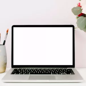 Green Beauty Blogger Shannon Sullivan's desk with laptop, flowers, and coffee