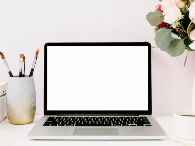 Green Beauty Blogger Shannon Sullivan's desk with laptop, flowers, and coffee