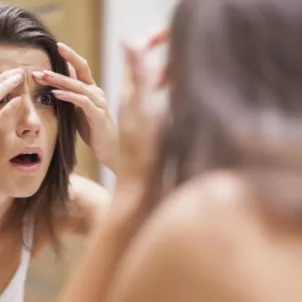 Woman examining forehead for acne