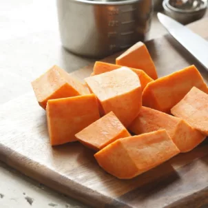Diced yams on wooden cutting board to make a fall recipe for radiant skin