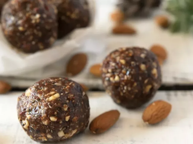 Photo of superfood energy balls with almonds on white tabletop