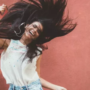 Woman dancing energetically to music to wake up from energy slump