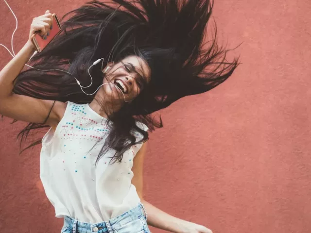 Woman dancing energetically to music to wake up from energy slump