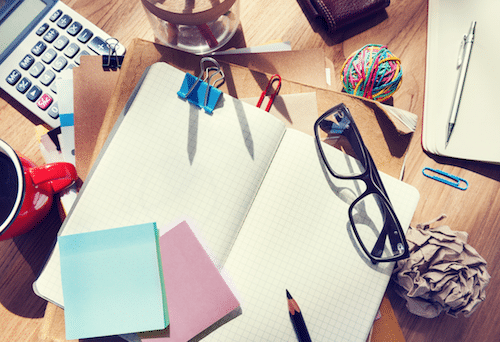 Scattered desk with office supplies on tiring work day