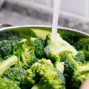 Woman washing broccoli for 21 day detox