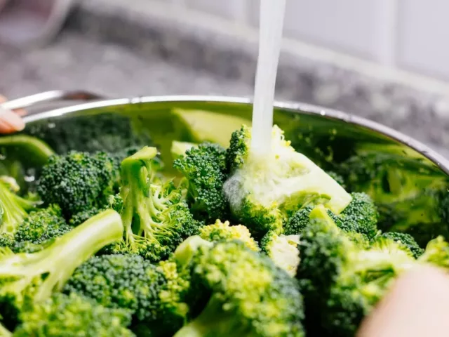 Woman washing broccoli for 21 day detox