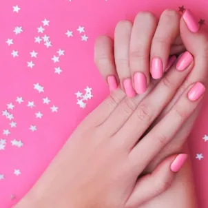 Woman's hands with pink nail polish on pink background after taking the best vitamins for nails