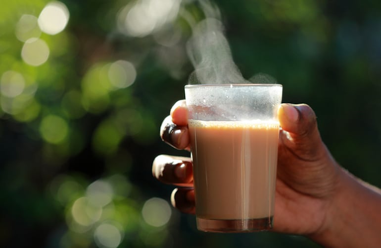 Woman holding a glass of chai tea with cinnamon to help curb her cravings on a sugar-free diet