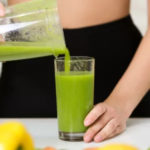 Woman pouring green smoothie into glass while on her no-sugar diet for 8 weeks