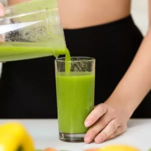 Woman pouring green smoothie into glass while on her no-sugar diet for 8 weeks