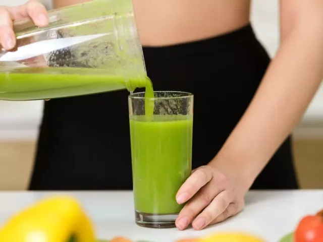 Woman pouring green smoothie into glass while on her no-sugar diet for 8 weeks