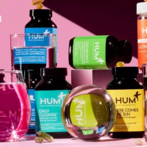 HUM supplements in a rainbow spectrum next to watery figurines on a pink background