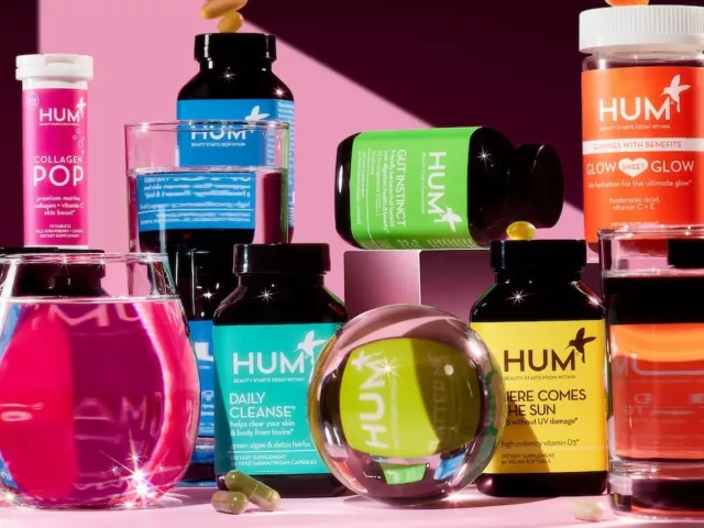 HUM supplements in a rainbow spectrum next to watery figurines on a pink background