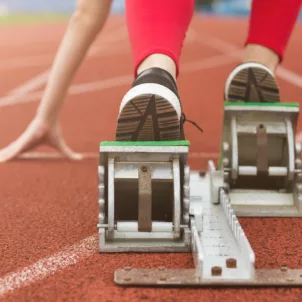 Woman on running track with her feet and hands in position to start running