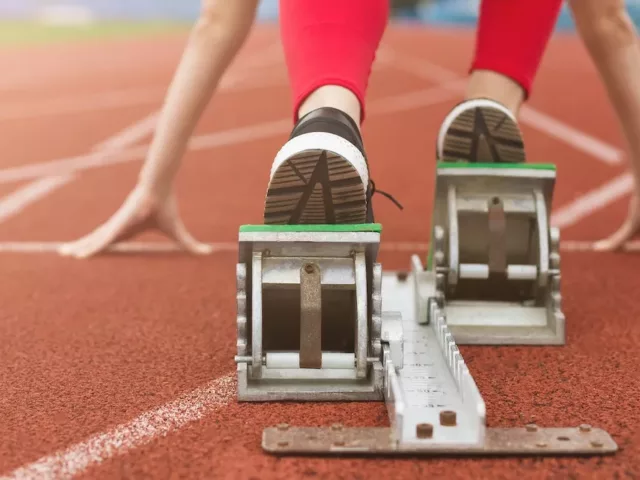 Woman on running track with her feet and hands in position to start running