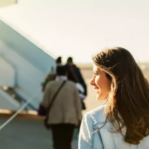 Woman on tarmac looking into the sun about to board an airplane