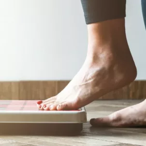 Woman following an extreme diet plan stepping onto scale to check her rapid weight loss