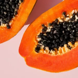 Fresh papaya cut in half on pink background