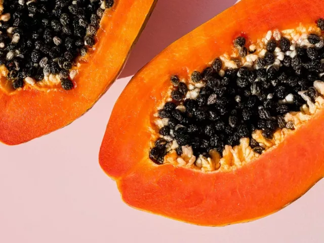 Fresh papaya cut in half on pink background