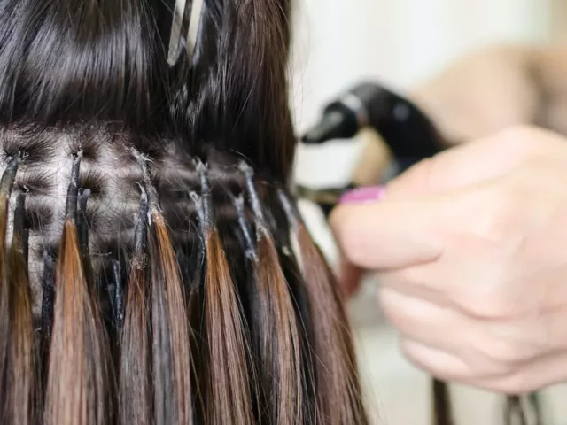 Woman getting hair extensions put in at a salon