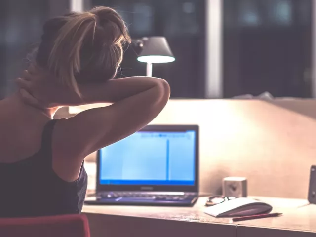 Woman stretching her neck while working late at the office