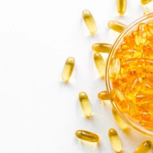 Bowl of omega fatty acid capsules on white table