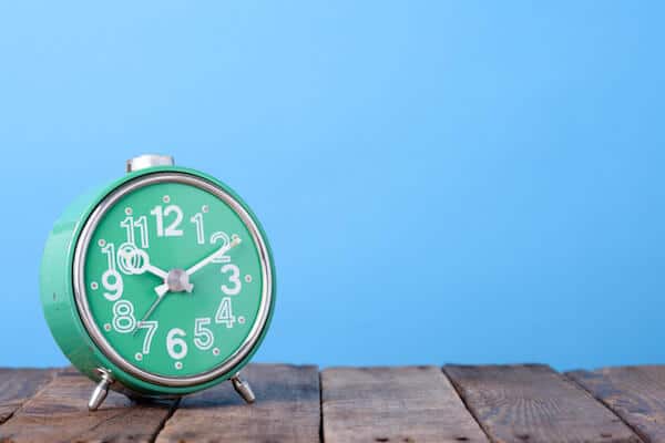 A retro looking clock in front of a blue background.