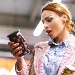 Woman in grocery store reading food label in shock