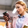 Woman in grocery store reading food label in shock