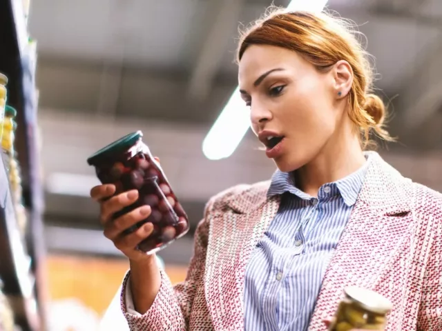 Woman in grocery store reading food label in shock