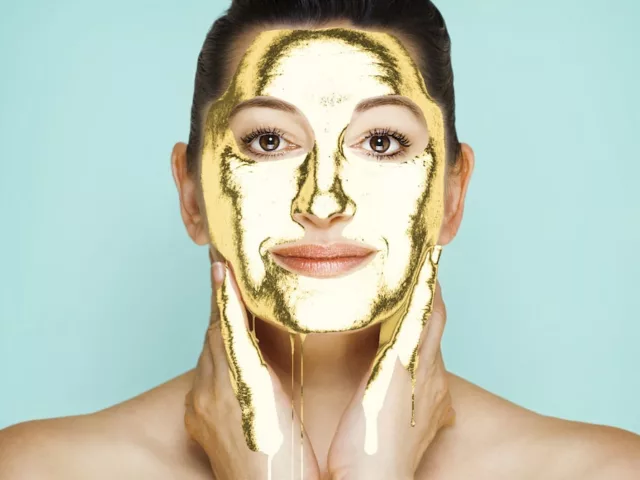 Woman with gold face mask dripping from her skin in front of Tiffany blue background
