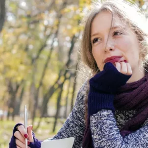 Woman journaling outdoors looking pensive