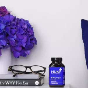 Bottle of HUM Beauty zzZz melatonin supplement on bedside table