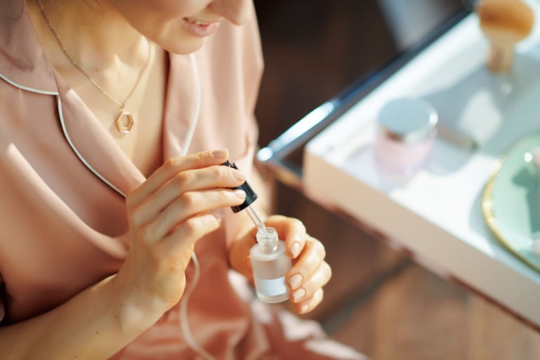 Woman with serum at her vanity using retinol in her 20s