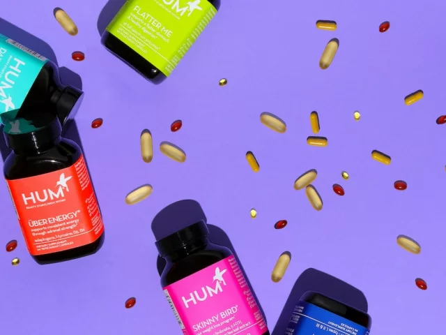 HUM Nutrition bottles with capsules spread on purple background