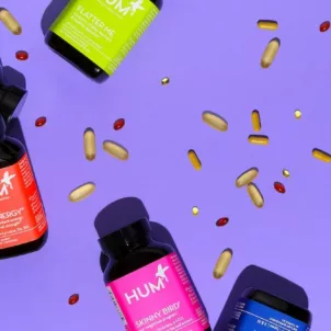 HUM Nutrition bottles with capsules spread on purple background