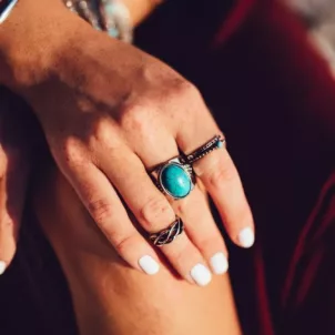 Woman wearing rings and white non-toxic nail polish