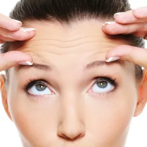 Woman looking up at and holding her wrinkled forehead