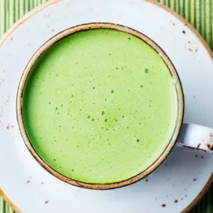 Morning matcha latte on saucer on green placemat