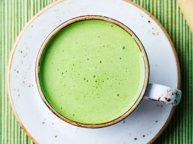 Morning matcha latte on saucer on green placemat