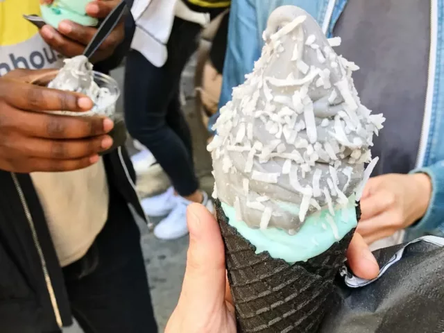 Grey goth ice cream with toppings in a black cone