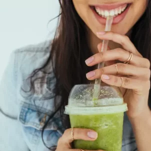 Woman drinking green smoothie while smiling