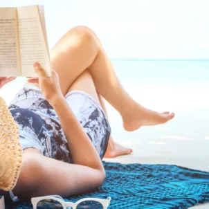 Woman on the beach, reading with all of her Labor Day Weekend essentials