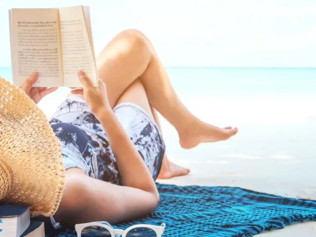 Woman on the beach, reading with all of her Labor Day Weekend essentials