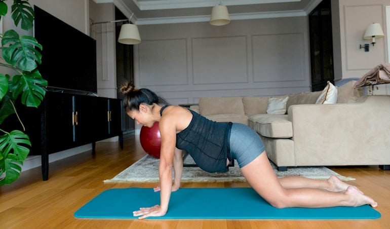 Pregnant woman doing yoga and Pilates at home to incorporate movement as part of her healthy pregnancy regimen