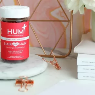 HUM Hair Sweet Hair gummies on marble pedestal on cute desk