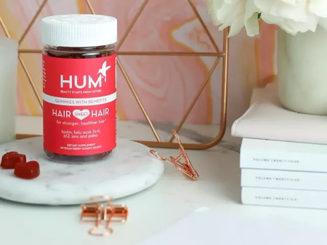 HUM Hair Sweet Hair gummies on marble pedestal on cute desk