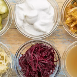 Ultimate Probiotic Foods, including pickles, kimchi, and sauerkraut in clear glass ramekins