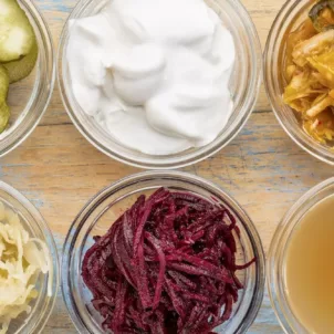 Ultimate Probiotic Foods, including pickles, kimchi, and sauerkraut in clear glass ramekins