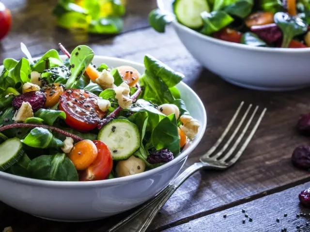 Healthy salad with sesame seeds and dried berries on wooden table